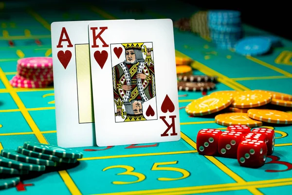 Een tweetal van koning en aas van de harten van speelkaarten op groene achtergrond van een speeltafel in een casino. Close-up van speelkaarten, chips en dobbelstenen voor het gokken, poker, blackjack, texas holdem. — Stockfoto