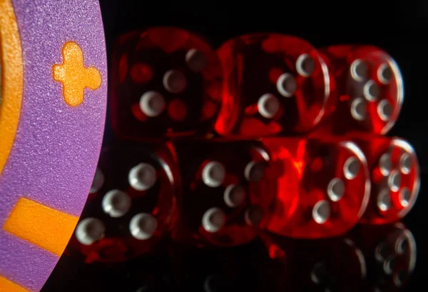 A set of red dice next to a casino chip on a black background. Close-up of dice for poker and craps. The concept of gambling, betting, money and success. — Stock Photo, Image