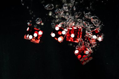 Suya batırılmış kırmızı zarlar. Hava kabarcıklarıyla suyun içinde yüzen bir dizi kumar zarını kapat. Kumarhanede kumar konsepti, risk, para, başarı.