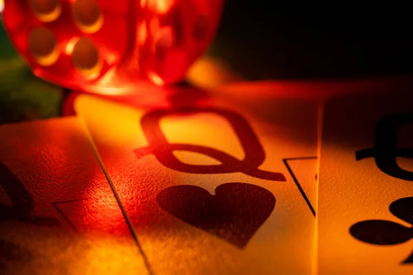 Kumarhanedeki kumar masasında üç kız ve sarı ışıkta kırmızı zarlarla oynanan bir kart seti. Poker ya da barbut oynuyorum. Kartlar kapanıyor. Kumar, eğlence ve başarı kavramı..