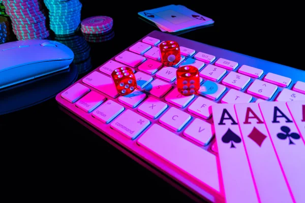 Computer keyboard and quads of four aces, illuminated with pink light on black background. Cards, casino chips and dice close up. Concept of gambling, online betting in casino. Online gambling. — Foto de Stock