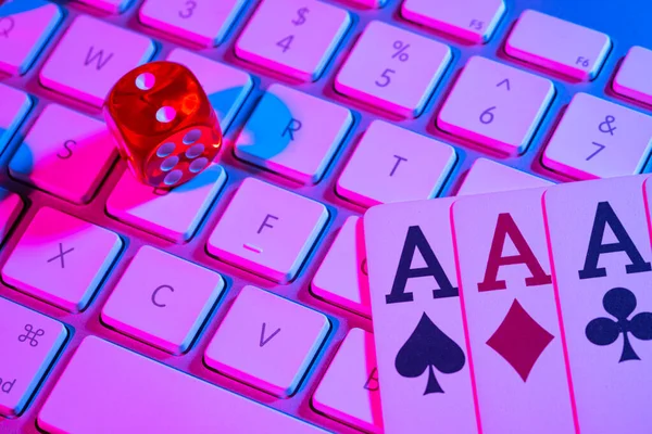 Computer keyboard and quads of four aces, illuminated with pink light on black background. Cards, casino chips and dice close up. Concept of gambling, online betting in casino. Online gambling. — Foto de Stock