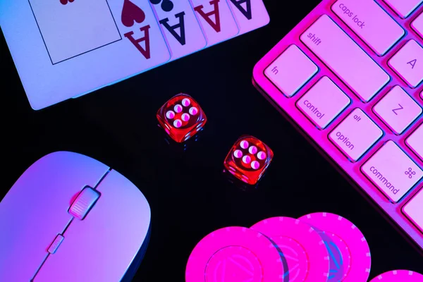 Teclado de computador e quádruplos de quatro ases, iluminados com luz rosa sobre fundo preto. Cartões, fichas de casino e dados de perto. Conceito de jogo, apostas online no casino. Jogo online. — Fotografia de Stock