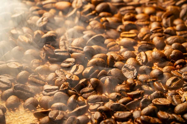 Freshly roasted brown coffee beans lying on burlap close up. Smoke comes from coffee beans. Food and drink background for cafe and cafeteria. Grains for preparation of an invigorating morning drink. — 스톡 사진