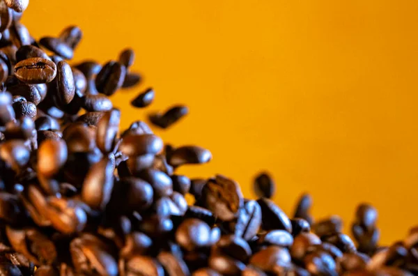 Explosion of freshly roasted brown coffee beans on yellow studio background. Fragrant coffee seeds scattering and falling close up. Coffee bean advertisement for cafe, cafeteria and restaurant. — 스톡 사진