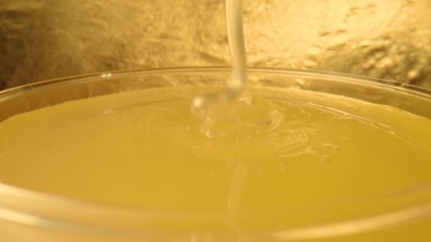 Een druppel dikke gouden honing die in een glas stroomt. Dicht macro shot van honingmelasse druipt in een glas vol zoete honing siroop. Zoet dessert. Achtergrond van biologisch en curatief voedsel. — Stockvideo