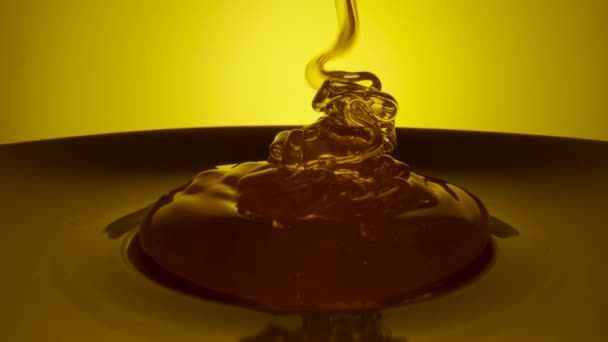 노란 배경에 두꺼운 시냇물을 쏟아 붓는 꿀 방울. 보는 사람의 꿀 이끼가 흘러내린다. 황금빛꿀 액을 클로즈업해서 양봉으로 만든 달콤 한 제품을 만들었습니다. 당밀이 쏟아져 나오고 있다. — 비디오