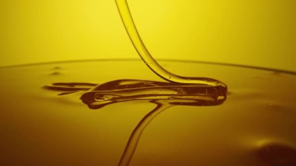 Honey dripping, pouring thick stream on yellow background. Viscous honey molasses flowing. Close up of golden honey liquid, sweet product of beekeeping. Sugar syrup is pouring flow. — Stock video