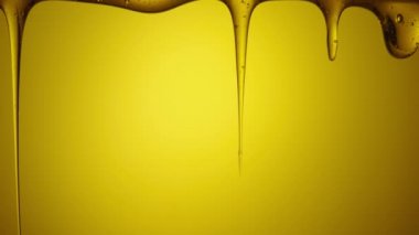 Sarı arka planda akan kalın altın bal damlaları. Tatlı nektara ya da pekmez dökülmesine yakın. Sıvı bal dökülüyor ve damlıyor. Şeker şurubu dökülüyor. Sağlıklı ve iyileştirici tatlı..