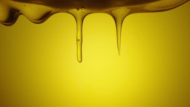 Ένα ρυάκι χρυσαφί παχύ μέλι χύνεται σε κίτρινο φόντο. Γλυκό μελάσα μελάσα χύνει από κοντά. Φυσικό βιολογικό μέλι, σιρόπι ή νέκταρ που ρέει. Γλυκό επιδόρπιο, μελισσοκομικό προϊόν, υγιεινή τροφή. — Αρχείο Βίντεο