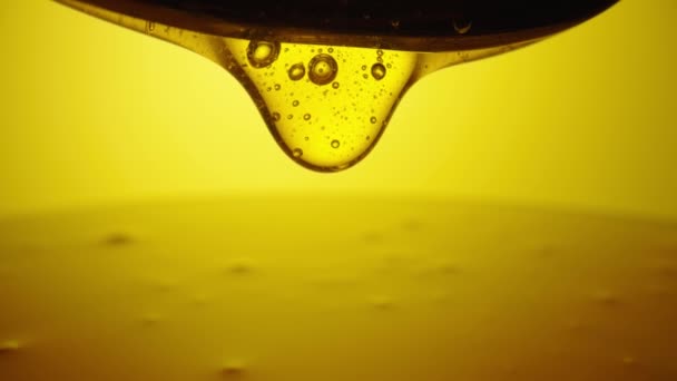 Drops of thick golden honey flowing down on a yellow background. Close up of sweet nectar or molasses being spilled. Liquid honey pours and drips. Sugar syrup is pouring. Healthy and curative dessert. — Stock video