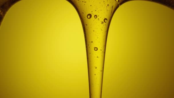 Drops of thick golden honey flowing down on a yellow background. Close up of sweet nectar or molasses being spilled. Liquid honey pours and drips. Sugar syrup is pouring. Healthy and curative dessert. — Vídeo de Stock