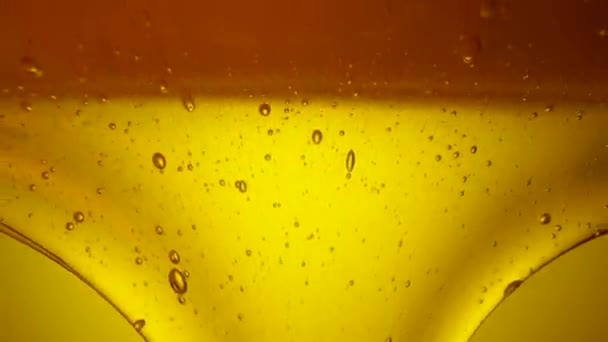Drops of thick golden honey flowing down on a yellow background. Close up of sweet nectar or molasses being spilled. Liquid honey pours and drips. Sugar syrup is pouring. Healthy and curative dessert. — Vídeo de stock
