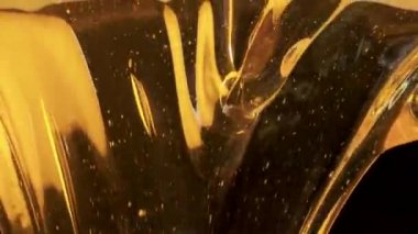 Siyah arka planda akan kalın altın bal damlaları. Tatlı nektara ya da pekmez dökülmesine yakın. Sıvı bal dökülüyor ve damlıyor. Şeker şurubu dökülüyor. Sağlıklı ve iyileştirici tatlı..