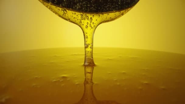 Honey dripping, pouring from spoon. Thick viscous honey molasses dripping. Close up of golden honey liquid, sweet product of beekeeping. Sugar syrup is pouring. Healthy and curative dessert. — стоковое видео