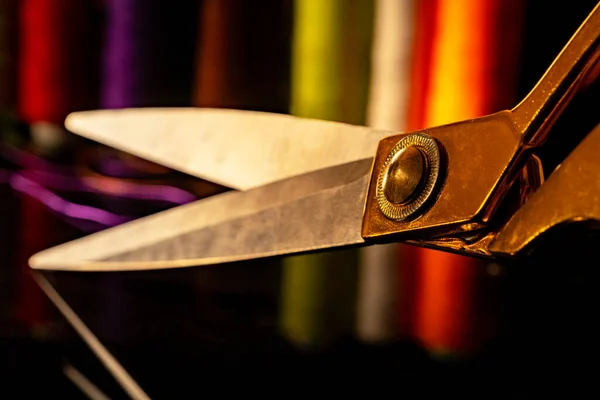 Tailors scissors with gold handles on a black background with colored spools of thread. Sewing tool for sewing, tailoring, cutting fabric, tailoring. Equipment for handmade or crafts in the workshop. — Stok fotoğraf