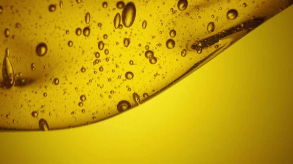 Kultainen paksu hunajavirta valuu keltaiselle pohjalle. Suloinen hunajamelassi kaataa läheltä. Luonnonmukaista hunajaa, siirappia tai nektaria virtaa. Makea jälkiruoka, mehiläishoitotuote, terveellinen ruoka. — kuvapankkivalokuva
