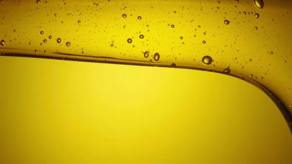 A stream of golden thick honey spills on a yellow background. Sweet honey molasses pours close up. Organic natural honey, syrup or nectar flowing. Sweet dessert, beekeeping product, healthy food. — Stock Photo, Image