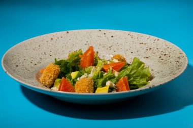 Greyfurtlu salata, yeşil marul, avokado, ton balığı ve peynirli mavi arka planda yakın plan. Restoran yemeği, sağlıklı bir tabak sebze ve meyve. İtalyan salatası. Fransız mutfağı.