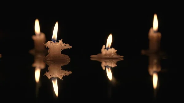 Burning Candles Black Background Candlelight Reflecting Glossy Surface Stubs Paraffin — Stock Photo, Image