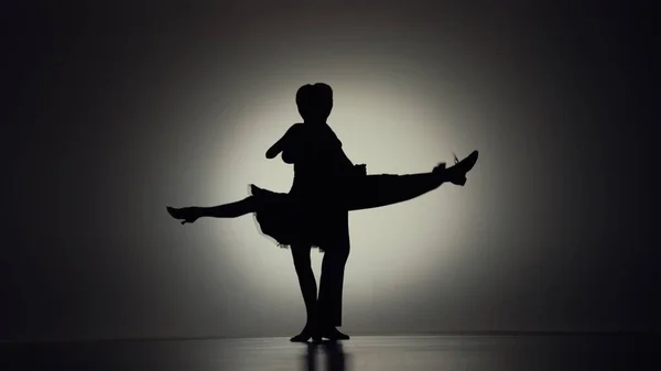 プロの舞踏家のペアによって行われる情熱的なタンゴ振付要素 男と女の黒いシルエットがバックライトで灰色の背景を移動します 感情愛ロマンス — ストック写真