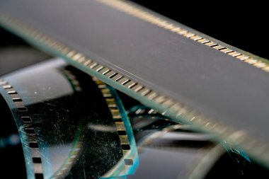 Çizik ve çiziklerle dolu eski analog filmlerden oluşan siyah kıvrımlı şeritler. Fotoğraf ya da film için video ya da film yakın çekim. Retro sinematografi, fotoğrafçılık, fotografik hafıza kavramı. Medya