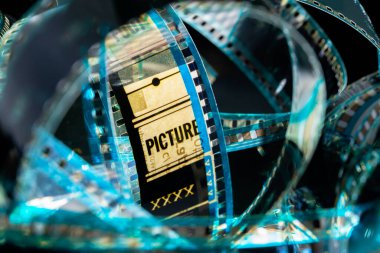 Kamera negatif film. Dönen bantlara, film deliklerine ve harf resimlerine odaklan. Eski renkli film. Çekim süreci için endüstri sembolü, retro görüntü, fotoğrafçılık