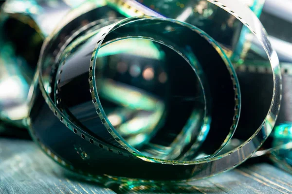 Yumuşak yeşil ışıkta spiral retro film şeridi. Bir fotoğraf ya da video kamera için eski film şeritleri bükülmüş. Sinematografi, fotoğrafçılık, fotografik hafıza kavramı.