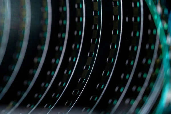 A roll of twisted retro film tape with green highlights. Twisted analog old strips of film for a photo or video camera close up. The concept of cinematography, photography, photographic memories