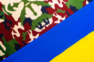 Ukrayna 'nın sarı mavi bayrağı ve askeri üniformanın kahverengi yeşil kamuflaj kumaşı. Kızışma kavramı, Ukrayna 'daki Rus askeri özel harekatı. Askeri haki üniforma çizimi ve Ukraynaca