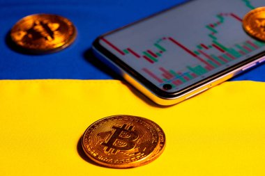 Üzerinde sarı mavi Ukrayna bayrağı olan kripto döviz piyasası grafiği olan Bitcoin ve cep telefonu. Sanal para için kripto para. Kripto para piyasasında siyasi düzenleme kavramı