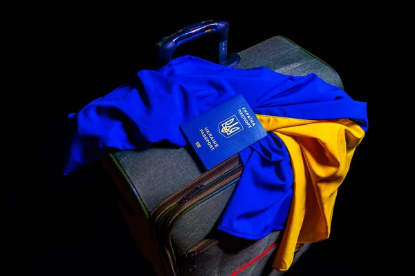 Biyometrik Ukrayna pasaportu ve Ukrayna 'nın mavi sarı bayrağı siyah arka planda bir bavulda. Ukrayna krizi, Rusya 'nın Ukrayna' daki saldırısı. Rusya 'nın Ukrayna' ya karşı savaşı. Turizm kavramı