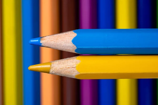 Blue and yellow pencils on the background of a set of colored pencils. Stationery tools for creativity and drawing. Childrens art school. Multicolored pencils close up