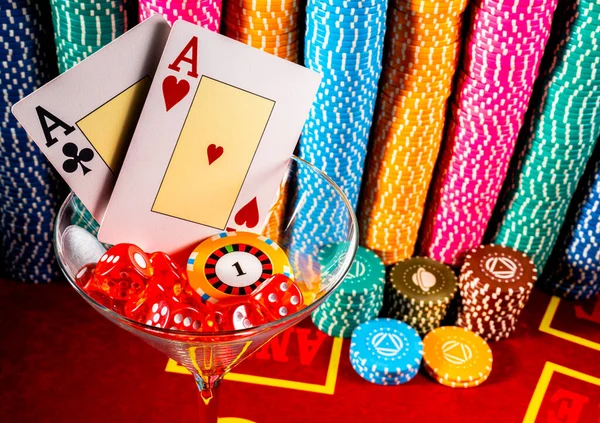 Two aces, a set of red dice and a chip in a martin glass on the background of casino chips. Close up of playing cards, chips and dice. Gambling background. Poker, roulette, blackjack. Betting, risk