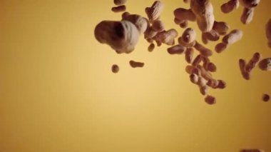 Sarı stüdyo arka planında kurutulmamış fıstık patlaması. Fındık fasulyesi su sıçratır ve etrafa saçılır. Tatlı yapmak için gerekli malzemeler. Bardaktan boşalırcasına fıstık. Kuru baklagiller, sağlıklı fındıklar