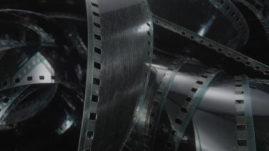 Spiral siyah film şeridi ya da fotoğraf negatifi. Fotoğraf ya da video kamera için eski siyah beyaz film şeritlerini analiz et. Seçici olarak film deliklerine odaklan. Sinematografi konsepti