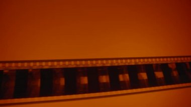 Mans eller eski film negatiflerini kırmızı ışıkta kaydırır. Retro film şeridi, yakın çekim. Fotoğraf ya da video kamera için eski siyah beyaz film şeritlerini analiz et. Retro sinematografi