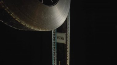 Kamera, eski siyah beyaz kaset ile makarada hareket eder ve yazıt Bitir 'e yaklaşır. Klasik film şeridi ya da fotoğraf negatifi. Eski sinema filmi, yakın plan. Sanayi sembolü