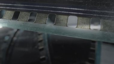 Kamera klasik negatif film. Seçici olarak film deliklerine odaklan. Eski bir sinema filmi. Sürtünme ve çiziklerle dolu siyah film şeridi. Çekim süreci için sanayi sembolü, retro sinematografi