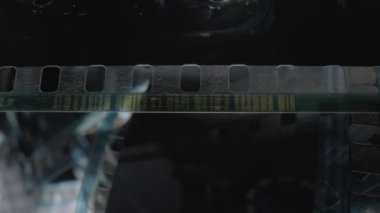 Kamera klasik negatif film. Seçici olarak film deliklerine odaklan. Eski bir sinema filmi. Sürtünme ve çiziklerle dolu siyah film şeridi. Çekim süreci için sanayi sembolü, retro sinematografi