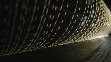 Aydınlatılmış eski film kaseti rulosu. Bir fotoğraf ya da video kamera için eski film şeritleri bükülmüş. Sinematografi, fotoğrafçılık, fotografik hafıza kavramı.