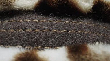 Benekli vahşi hayvan kürkünün dokusu. Tüylü beyaz kahverengi kürk, yumuşak sıcak kürk manto, yapay kürklü kumaştan giysiler. Tüylü tüylü kumaş. Moda endüstrisi tekstili. Çok yakın çekim.