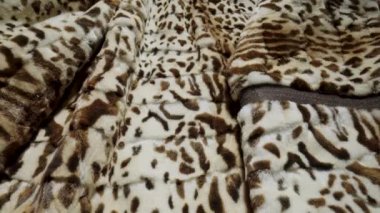 Benekli vahşi hayvan kürkünün dokusu. Tüylü beyaz kahverengi kürk, yumuşak sıcak kürk manto, yapay kürklü kumaştan giysiler. Tüylü tüylü kumaş. Moda endüstrisi tekstili. Çok yakın çekim.