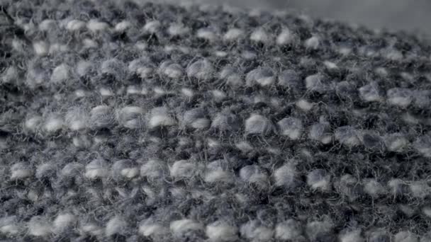 マクロでニットグレーウール生地 暖かい服 セーター 居心地の良い再生 ベッドスプレッド スカーフの構造 ウールで作られた編んだ柔らかい素材 ニットテキスタイルの背景 ふわふわの極端なクローズアップ — ストック動画