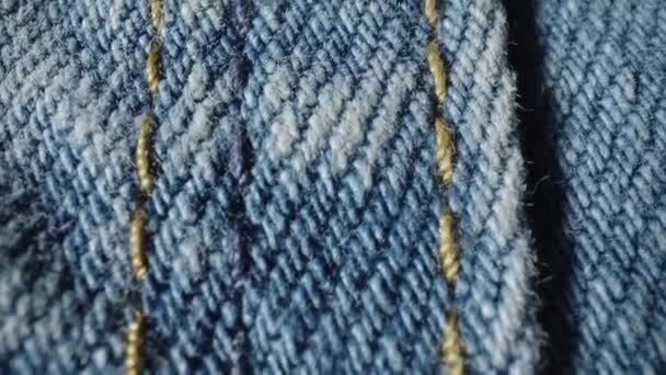 宏观拍摄蓝色斜纹棉布牛仔裤材料 服装的结构 纺织材料 棉织物 服装面料质感非常接近 用黄色线缝制的缝线 — 图库视频影像