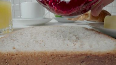 Kavanozdan ekmek ekmeğine akan ahududu reçeli. Sandviçi tatlı reçelle kapat. Sabahları mutfakta lezzetli bir kahvaltı hazırlıyorum. Tatlı, lezzetli, fast food.