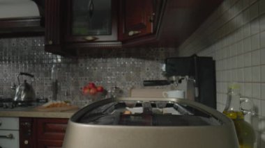 Mutfak masasındaki ekmek kızartma makinesinden fırlayan dilimlenmiş beyaz ekmek. Tost makinesinden fırlayan kızarmış ekmek ve çıtır çıtır ekmek. Kahvaltı için sabah yemeği hazırlıyorum. Sıcak tost.