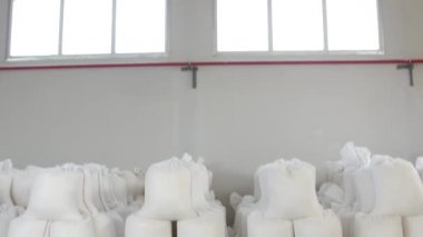 Üretim deposunda un, şeker, grat veya makarna içeren beyaz çuvallar. Bir endüstriyel girişimin deposunda paketlenmiş malların depolanması. Tahta paletlerde bir çanta dolusu, paketlenmiş ürünler...