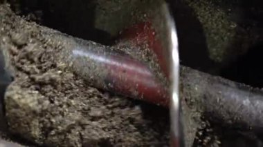 Metal çapa döner ve yağ çıkarmak için ayçiçeği tohumlarını öğütür. Fabrikadaki ayçiçeği yağı üretimi. Modern endüstriyel ekipmanlarla yağ tohumları üretmek, ezmek, öğütmek. Kapat.