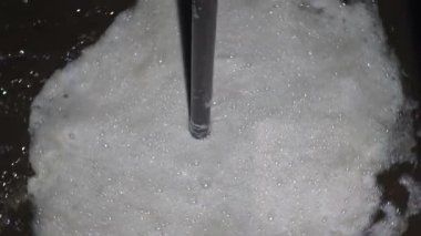 Taze sıkılmış ayçiçeği yağı ve kabın içinde dönen beyaz köpük. Ay çekirdeği veya yağ çekirdeği sıktıktan sonra yağlı kahverengi sıvı. Petrol çıkarmak için endüstriyel üretim. Kapatın. Yavaş çekim